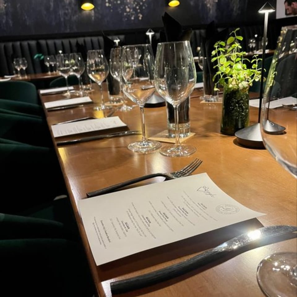 A long wooden table set with wine glasses, menus, and cutlery at Argyle Restaurant.