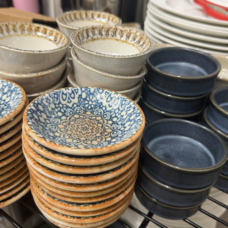 Stacks of small, decorative ceramic bowls in blue, white, and brown patterns, alongside plain blue bowls.