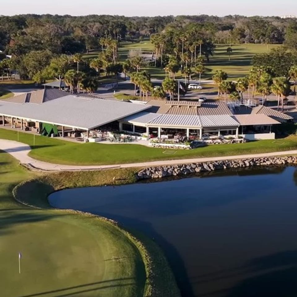 Aerial view of Argyle Restaurant, a large building with outdoor seating, next to a golf course and pond.