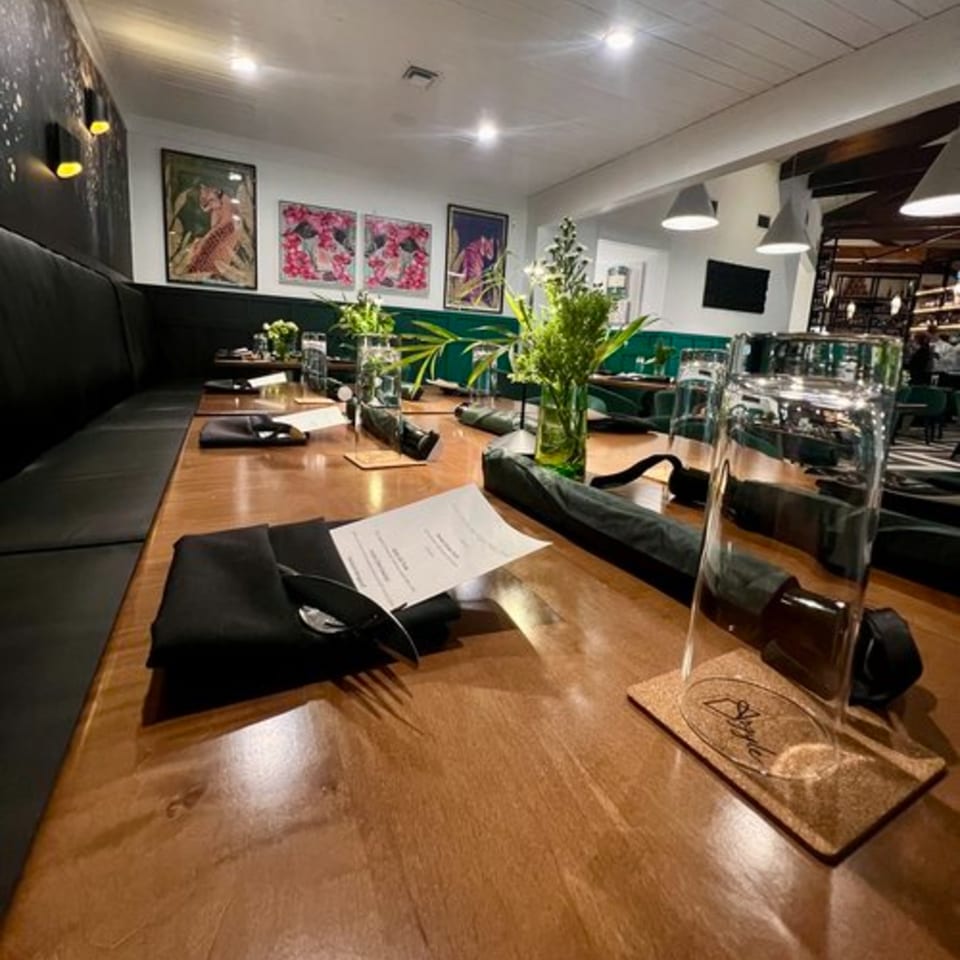 Long wooden table set with black napkins, menus, and green plant centerpieces at Argyle Restaurant.